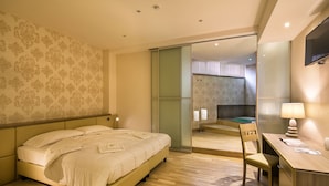 A modern hotel room with a bed, desk, chair, and a sliding door leading to a bathroom. - UmbriaVerde Sporting & Resort (Massa Martana)