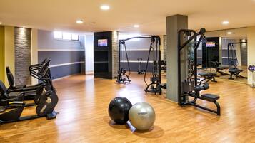 Un gimnasio con equipo de ejercicio, suelo de madera y un espejo.