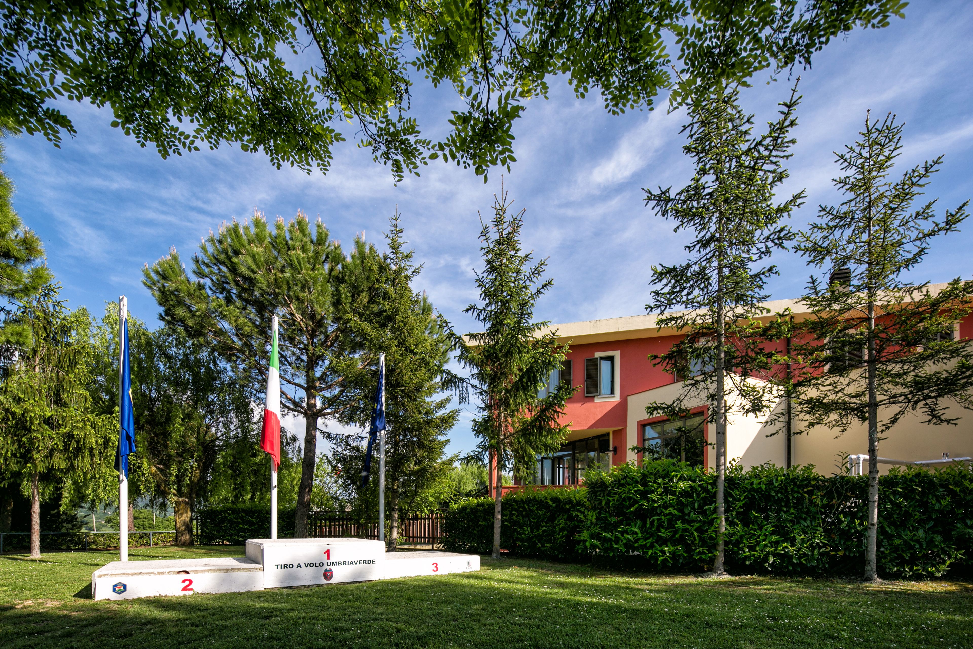A grassy area with a podium, flags, and a building in the background.