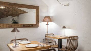 Un comedor con una mesa de madera, sillas de mimbre y un espejo en la pared.