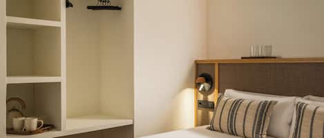 A hotel room with a bed, a wardrobe, a bedside table with a lamp, and a tray with cups and a teapot.