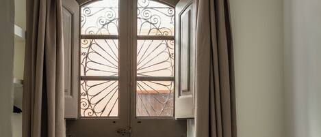 A room with a bed, a chair, and a window with curtains.