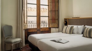 A hotel room with a large bed, a chair, and a window with a view of a building. - BYPILLOW Cluc Begur (Begur)