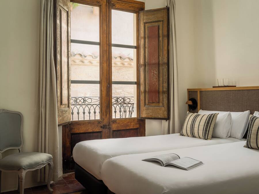 Habitación de hotel con una cama grande, una silla y una ventana con vistas a un edificio.