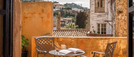 A balcony with two metal chairs, a table, and a potted plant.