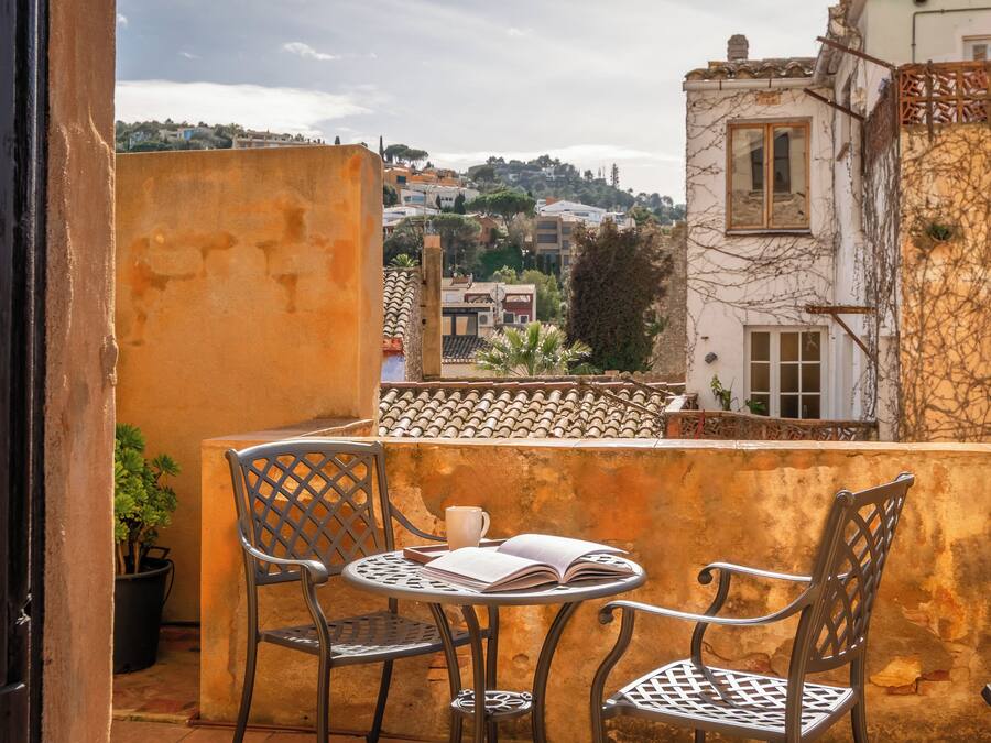 Ein Balkon mit zwei Metallstühlen, einem Tisch und einem Blumentopf.