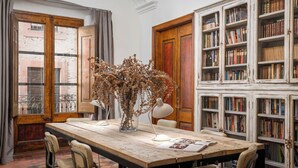 A dining area with a wooden table, chairs, a vase with dried plants, and a bookshelf filled with books. - BYPILLOW Cluc Begur (Begur)