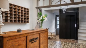 A reception desk with a laptop, a vase of flowers, and a wooden panel with the text "BYPILLOW Che Bregu". - BYPILLOW Cluc Begur (Begur)