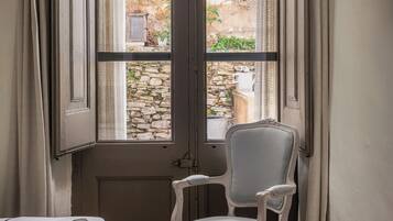 Una habitación con un ventanal grande, una silla blanca y una cama.