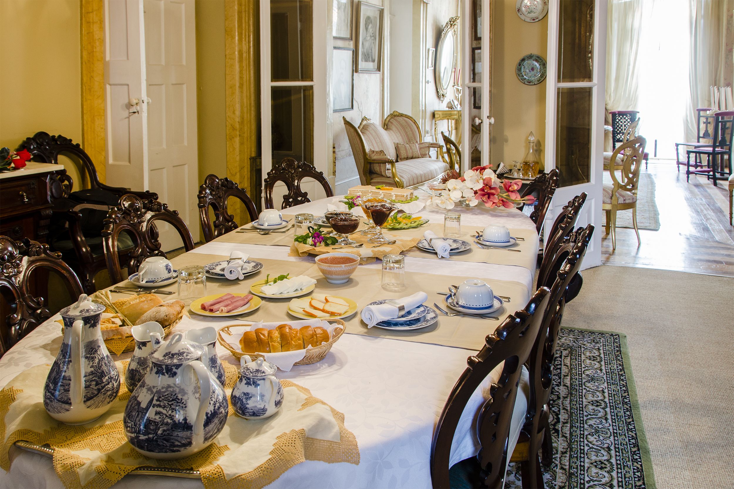 A dining room with a long table set for a meal, surrounded by ornate chairs.