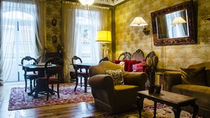 A room with a wooden floor, a sofa, a table, and a chandelier.