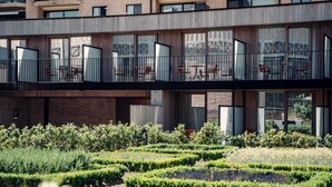 A modern building with a courtyard featuring neatly trimmed hedges and a small water feature. - Casino Hotel (Koksijde)
