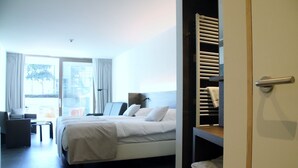 A hotel room with a bed, a desk, a chair, and a view of the outdoors. - Casino Hotel (Koksijde)