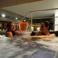 Two people in a hot tub with a bottle of orange juice.