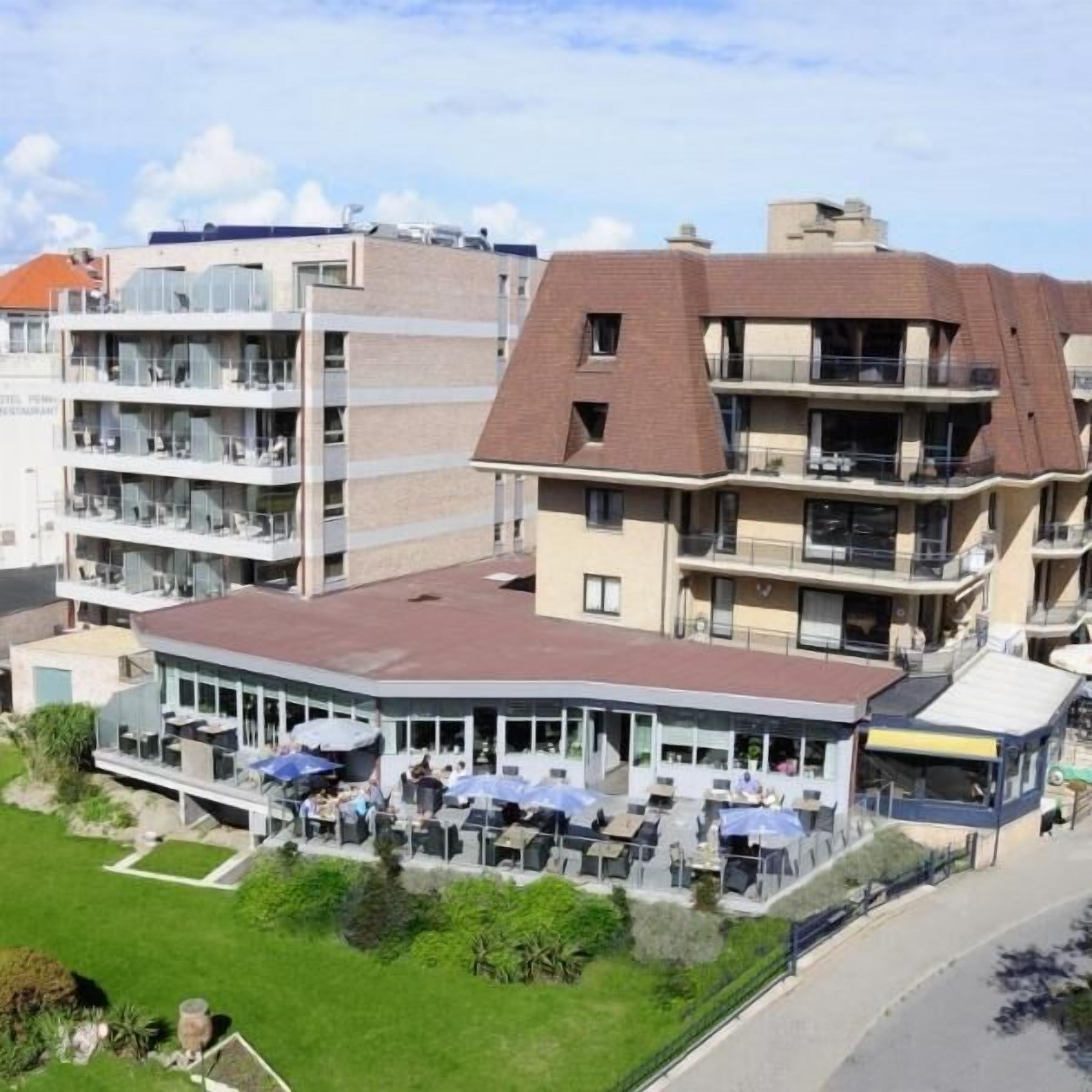 Een meerhoog hotel met terras en een restaurantgedeelte.
