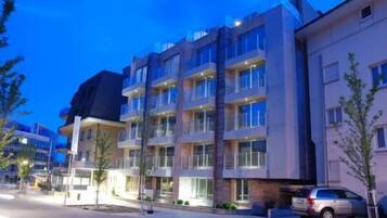A multi-story hotel with balconies, a parking area, and a street view.