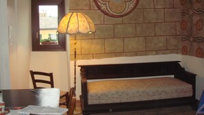 Quarto com cama, luminária, cadeira e parede com padrão de azulejos decorativos.