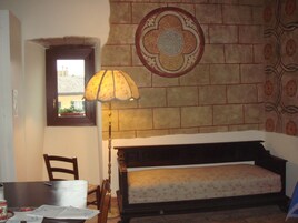A room with a bed, a lamp, a chair, and a wall with a decorative tile pattern.