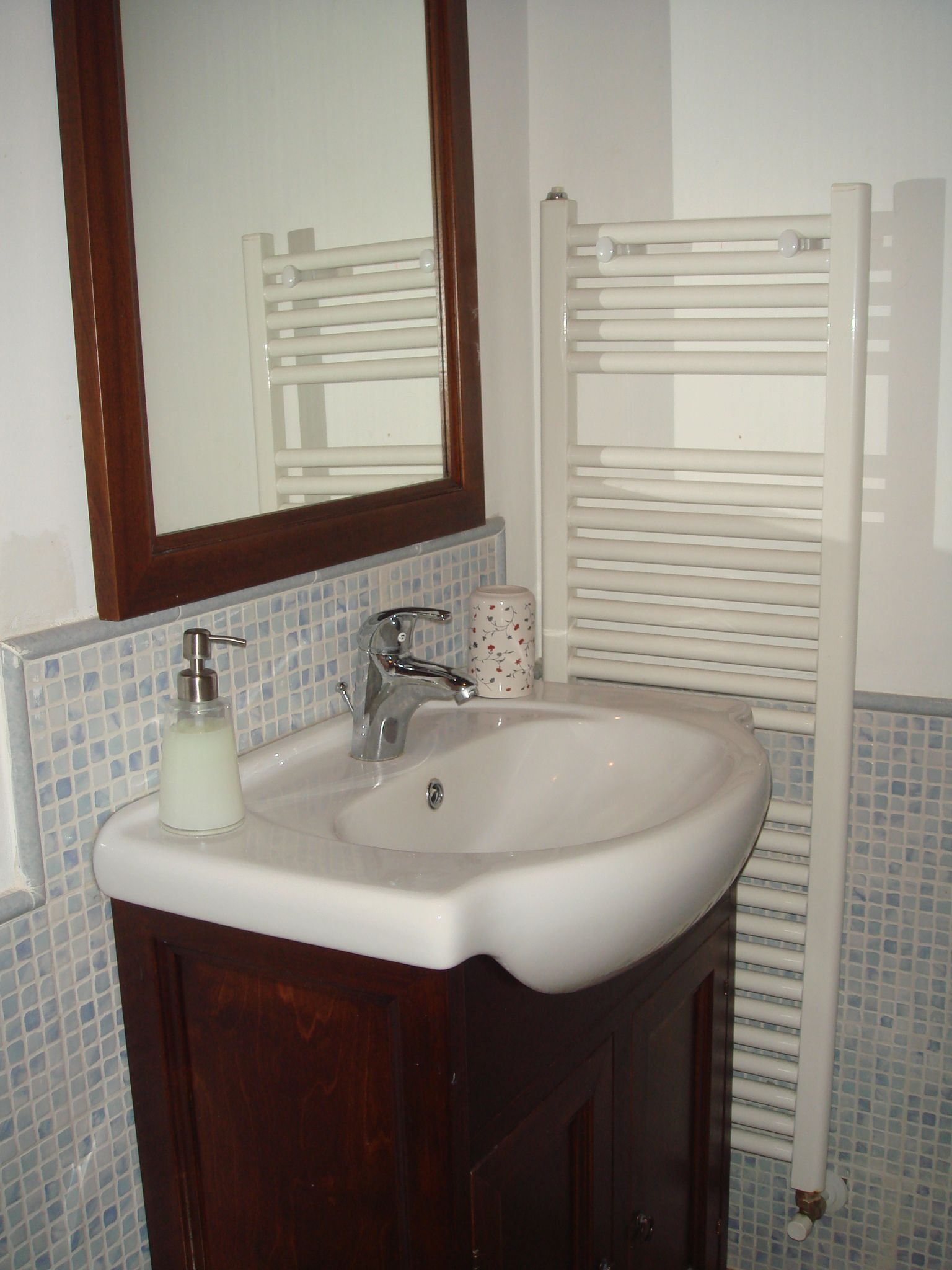 A bathroom with a white sink, a mirror, and a towel rack.