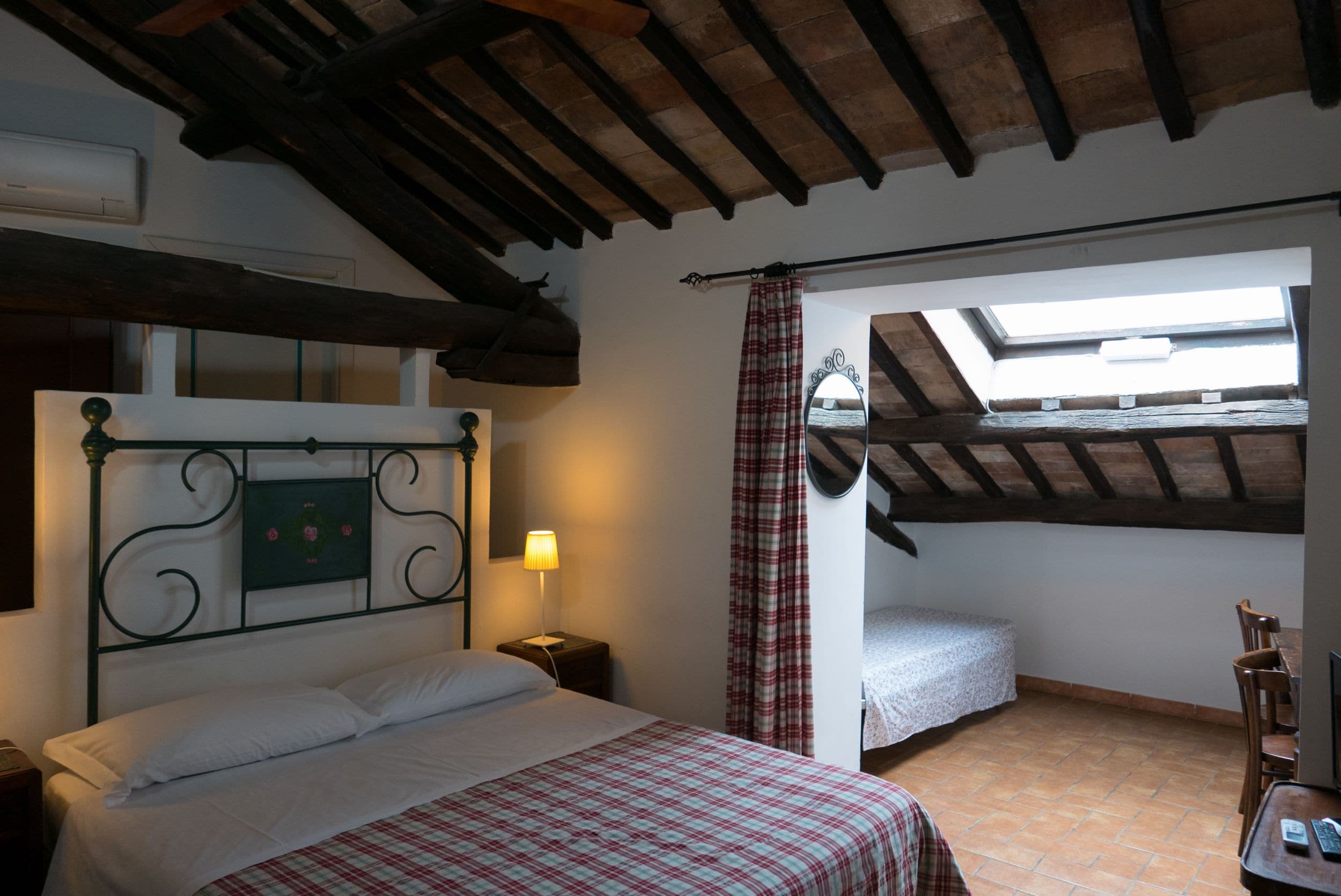 A bedroom with a bed, a nightstand, a lamp, a window with a view, and a skylight.