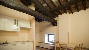 Uma cozinha com armários brancos, uma mesa de jantar de madeira com cadeiras e uma janela com vista.