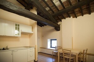 A kitchen with white cabinets, a wooden dining table with chairs, and a window with a view.