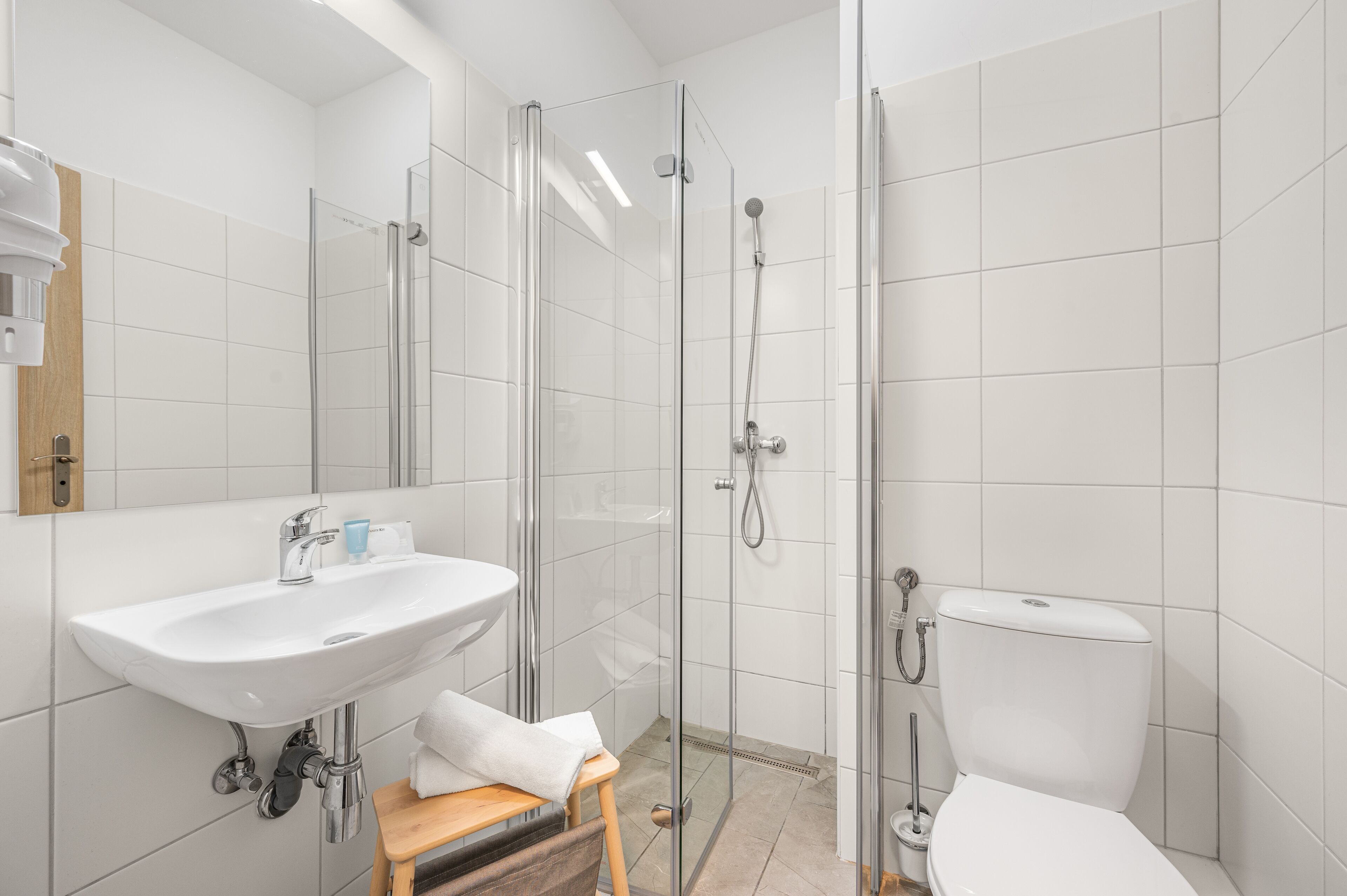 A modern bathroom with a glass-enclosed shower, a white sink, and a toilet.