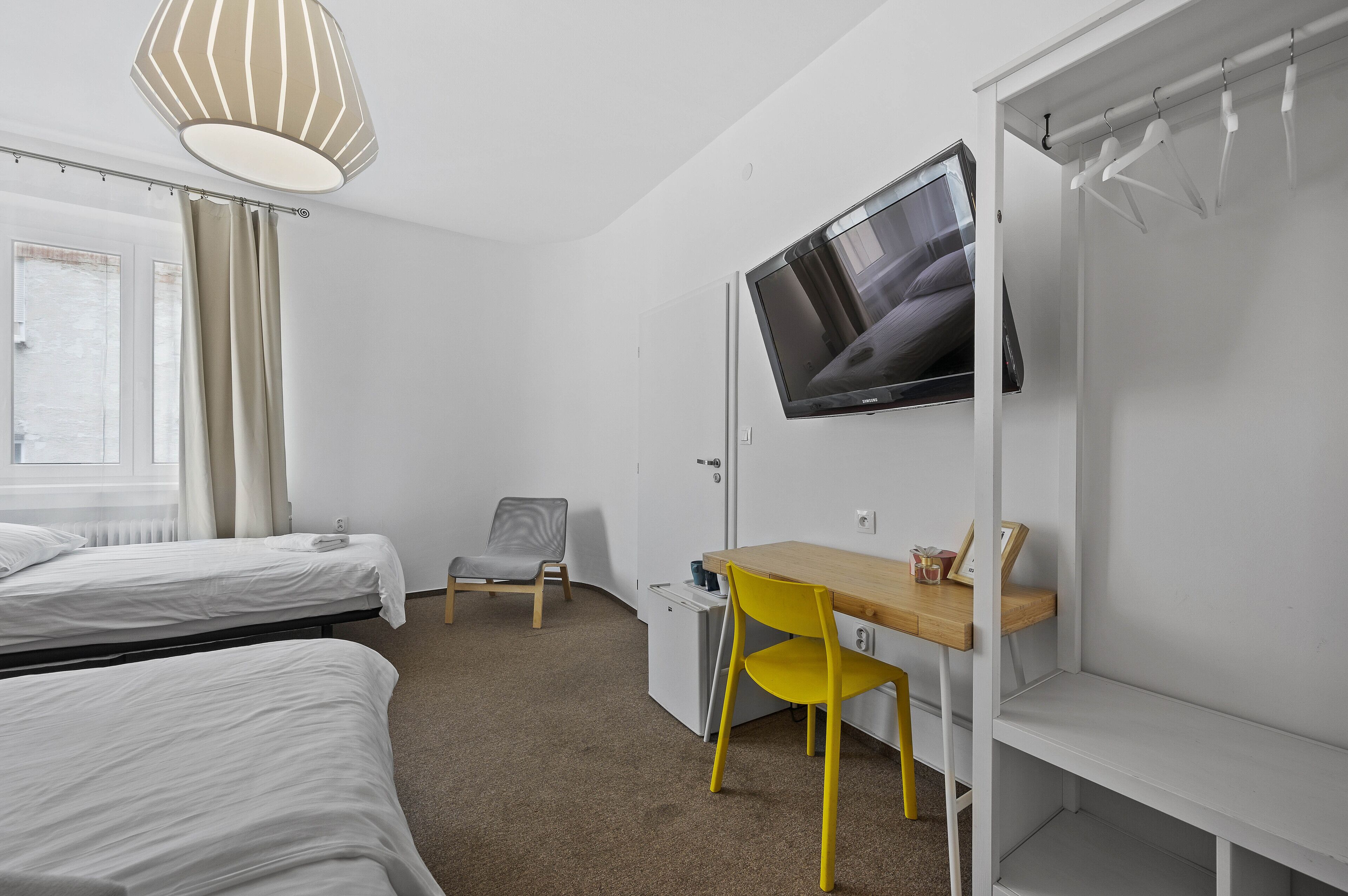 Une chambre avec deux lits, un bureau, une chaise, une télévision et une armoire.