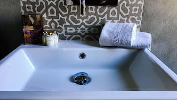 Un lavabo de salle de bain avec un miroir, une serviette et deux flacons de parfum.