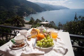 A table with breakfast items and a scenic view of the sea. - Hotel Suisse Bellevue (Monterosso al Mare)