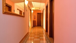 A hotel hallway with a checkered floor, a large mirror, and doors leading to rooms. - Hotel Amba Alagi (Mestre)