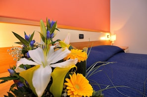 A hotel room with a bed, a nightstand, and a wall-mounted lamp.