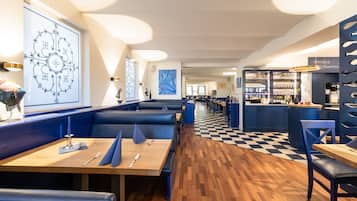 Un restaurante con cabinas, mesas de madera y suelo a cuadros.