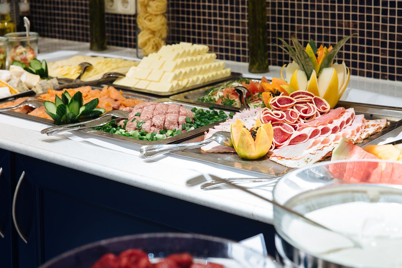 A buffet with various food items including meats, cheeses, and fruits.