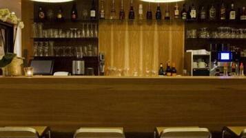 A bar area with a wooden counter, shelves of bottles, and bar stools.