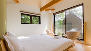 Un dormitorio con una cama grande, una ventana y vista a una casa.