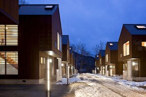 A row of modern, wooden apartment buildings with large windows and a paved pathway in between. - Gakuto Villas (Hakuba)