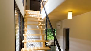 Una escalera de madera con barandales negros que lleva a un piso superior.