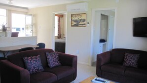A living room with two sofas, a coffee table, and a TV mounted on the wall.