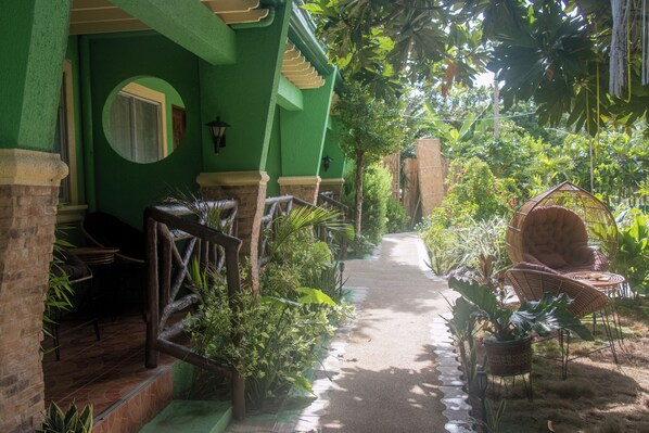 A covered outdoor area with a pathway, wicker furniture, and lush greenery. - Moonlight Resort (Daanbantayan)