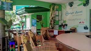 A reception area with a counter, wicker chairs, a ceiling fan, and a sign for Moonlight Resort. - Moonlight Resort (Daanbantayan)