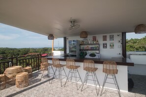 A bar area with a counter, bar stools, and a view of the landscape. - Moonlight Resort (Daanbantayan)