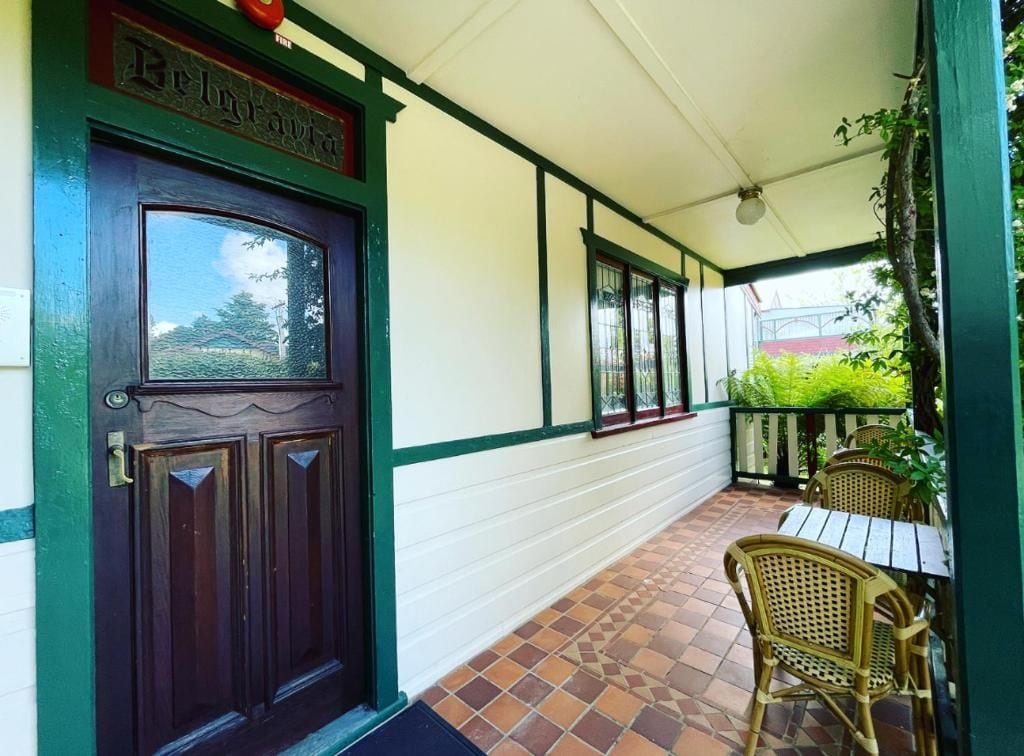 A covered porch with a wooden door, a tiled floor, and wicker furniture.