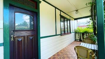 A covered porch with a wooden door, a tiled floor, and wicker furniture.