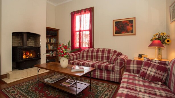 Una sala de estar con chimenea, un sofá a cuadros, una mesita de centro y una estantería.