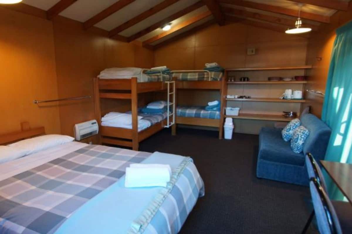 A room with a large bed, two bunk beds, a desk, and a chair.