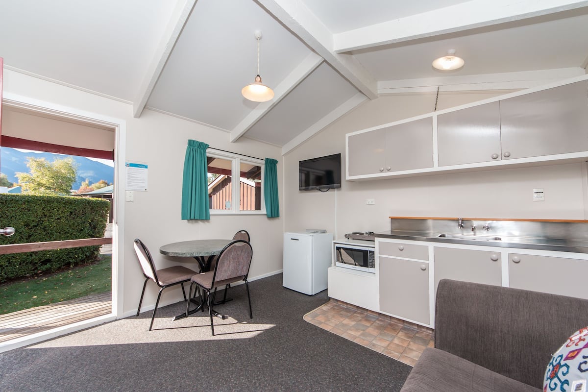 A compact kitchen with a dining area, a TV, and a small refrigerator.