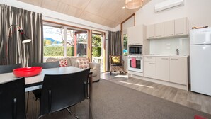Een moderne keuken met witte kastjes, een ingebouwde oven en een koelkast. Er is een zithoek met een tafel en stoelen, en een bank met een decoratief kussen.