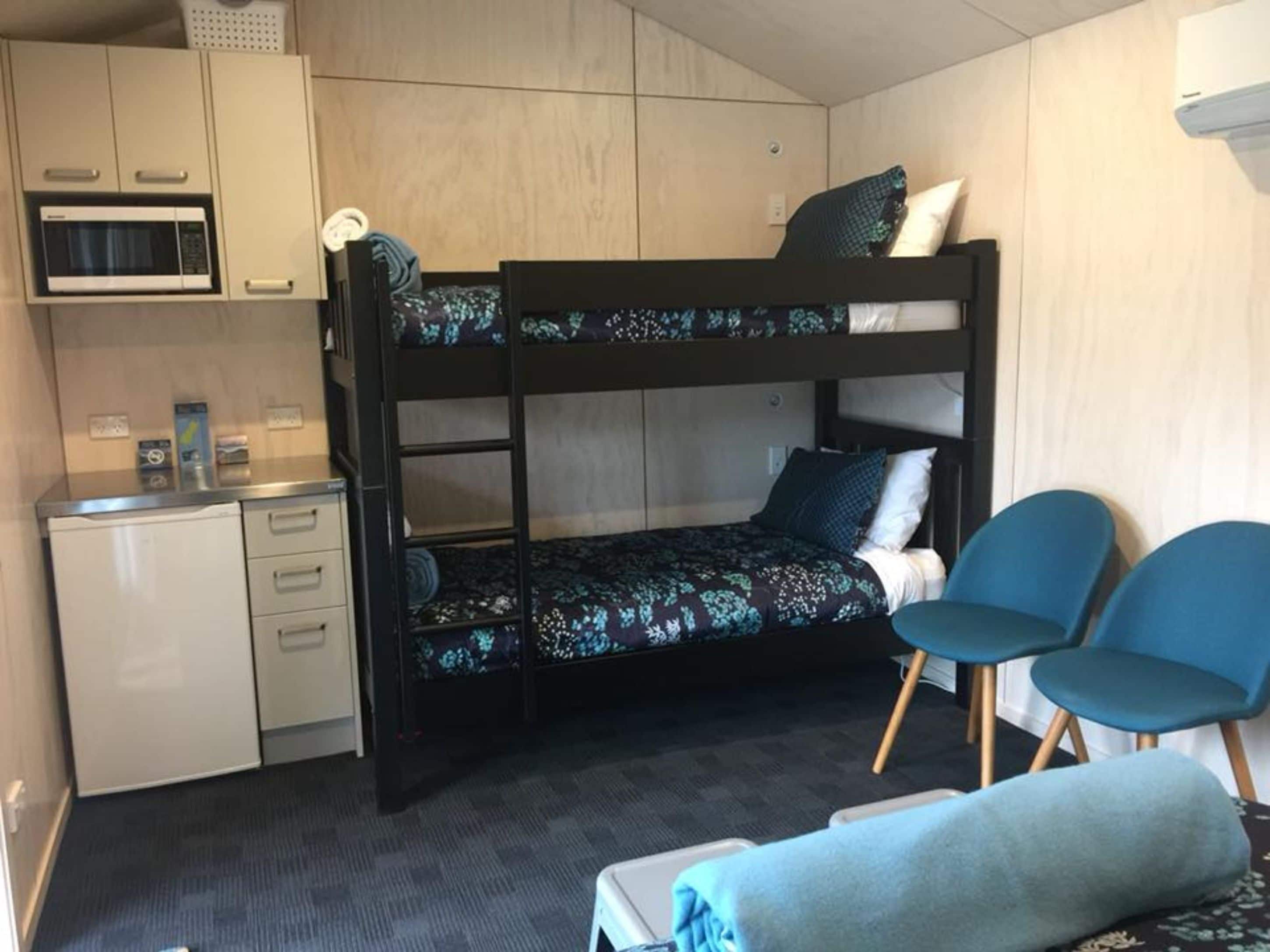 A bunk bed with a desk and chair, a microwave, and a small kitchenette.