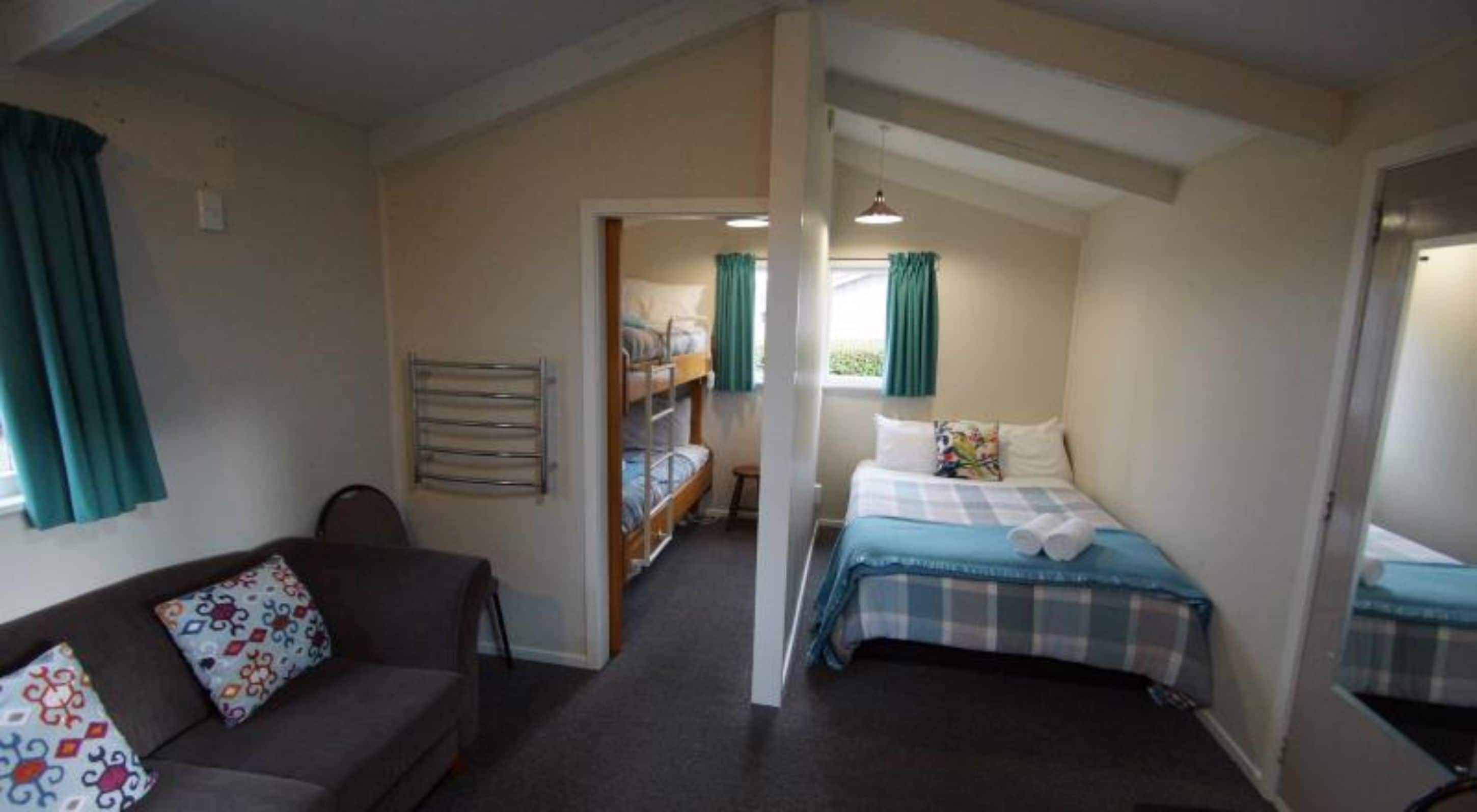 Una habitación con literas, una cama individual, un sofá y una pequeña mesa.